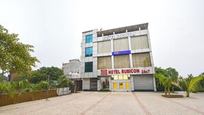 A modern hotel building with a sign indicating it has 24x7 rooms and a 7-day banquet option. - Fabhotel Rubicon (Faridabad)