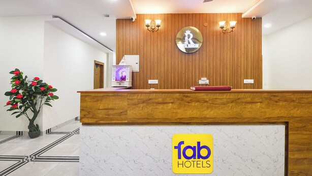 A hotel reception desk with a wooden panel wall, a reception counter, a ceiling fan, and a logo for 'fab hotels'. - Fabhotel Rubicon (Faridabad)