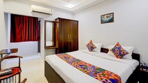 A hotel room with a bed, a wardrobe, a mirror, and a painting on the wall. - Fabhotel Jaswitha Grand (Hyderabad)