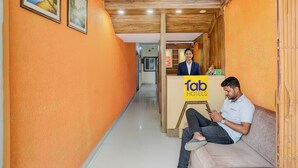 A hotel reception area with a wooden ceiling, orange walls, and a reception desk labeled 'fab hotels'. - Fabhotel Yash Stay Inn (Bhopal)