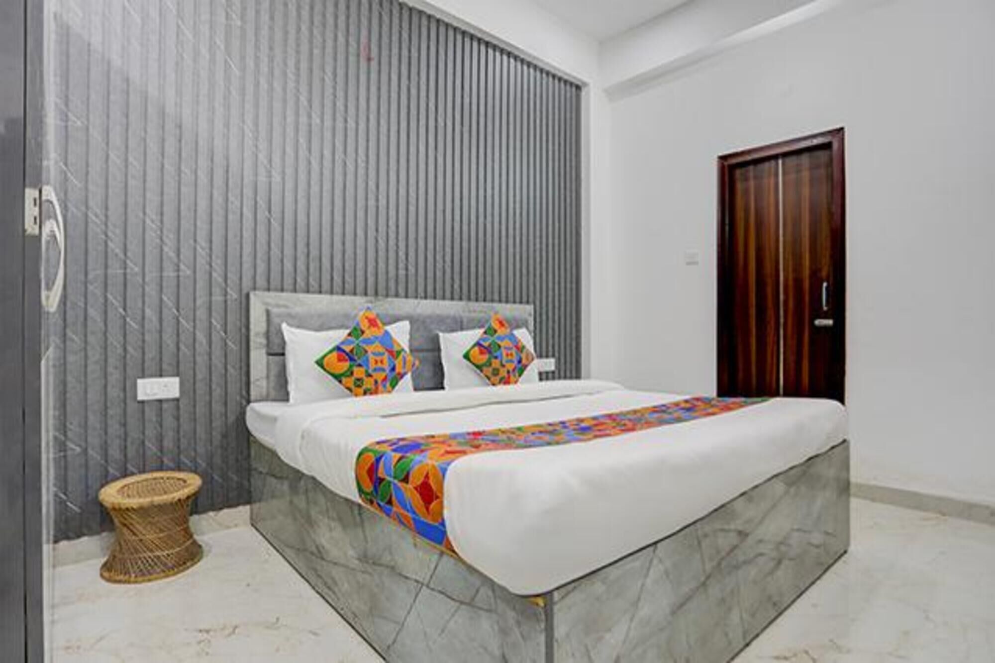 A bedroom with a bed, a wooden door, and a grey wall.