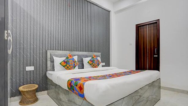 A bedroom with a bed, a wooden door, and a grey wall. - Fabhotel Kashi (Varanasi)