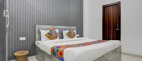 A bedroom with a bed, a wooden door, and a grey wall.