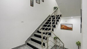 A staircase with a metal railing, a wall-mounted picture, and a potted plant. - Fabhotel Kashi (Varanasi)