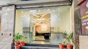 A hotel entrance with a glass door, potted plants, and a visible interior with a ceiling fan. - Fabhotel Asian Heights (Hyderabad)