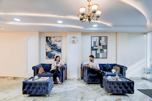 A modern lobby with two dark blue sofas, a chandelier, and marble flooring. - Fabhotel Asian Heights (Hyderabad)
