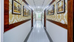 A long, narrow hallway with patterned wallpaper and framed pictures on the walls. - Fabhotel Asian Heights (Hyderabad)