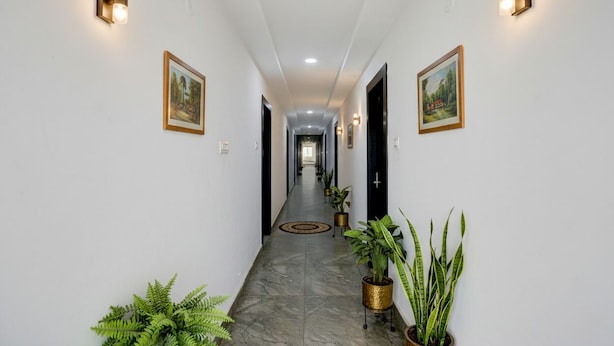 A hallway with white walls, framed pictures, and potted plants. - Fabhotel High Rise Near Airport (Hyderabad)