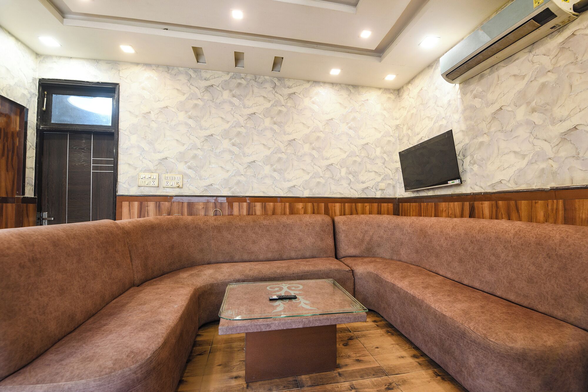 Una sala de estar moderna con un sofá curvo, una mesa de centro de vidrio y suelo de madera.