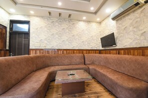 A modern living room with a curved sofa, a glass coffee table, and a wooden floor. - Fabhotel Shiv Palace (New Delhi)