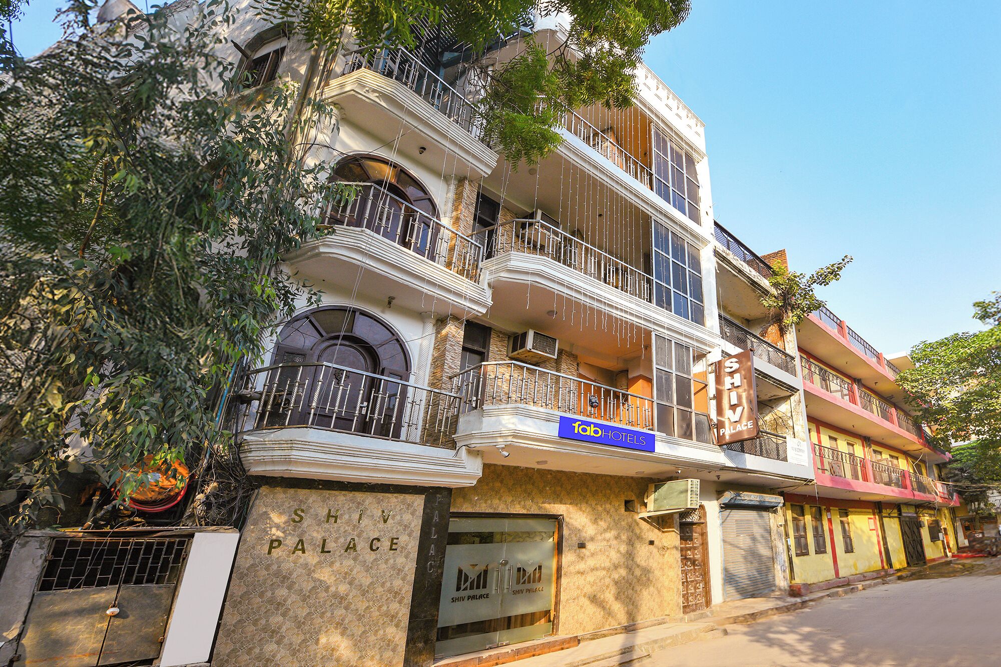 A multi-story building with balconies, a sign for Shiv Palace, and a facade with decorative elements.