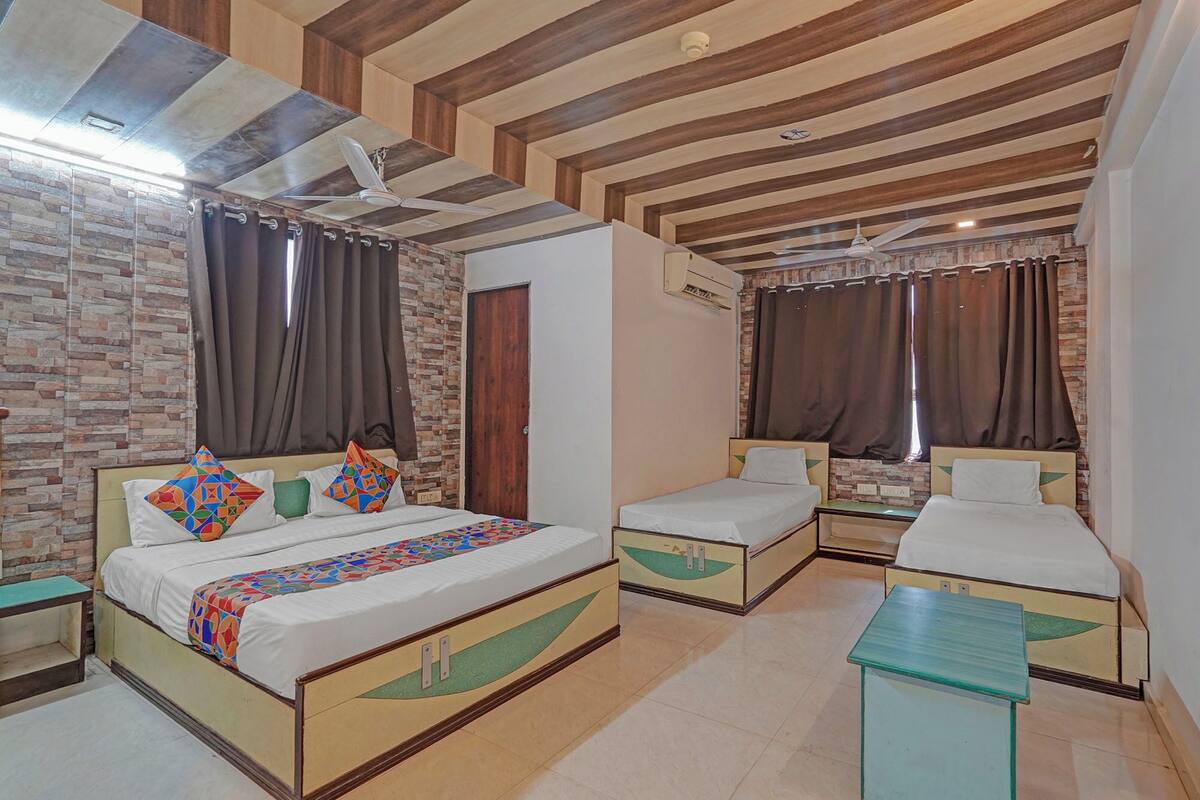 Habitación de hotel con dos camas, una mesita pequeña y un ventilador de techo.