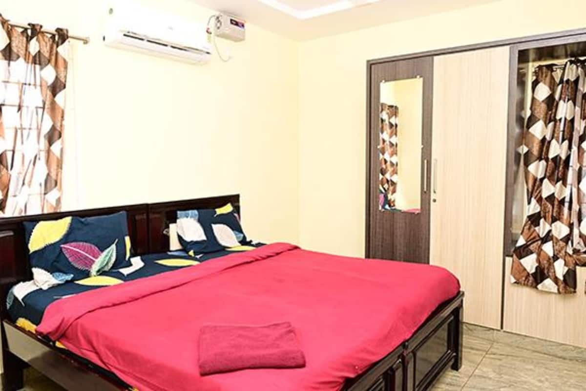 Un dormitorio con cama, aire acondicionado, armario y cortinas estampadas.