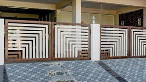 A gated entrance with a patterned metal gate and a tiled floor. - Fabexpress Coastal Suites (Kakinada)