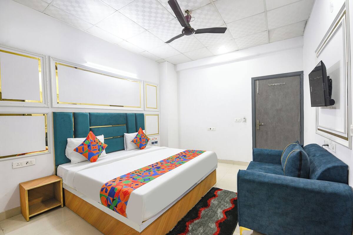 Una camera da letto moderna con un letto, un divano blu, una ventola a soffitto e una porta.
