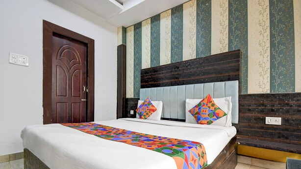 A hotel room with a bed, a wooden headboard, striped wallpaper, and a door. - Fabhotel Park Avenue (Lucknow)
