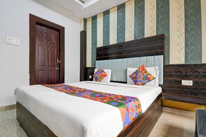 A hotel room with a bed, a wooden headboard, striped wallpaper, and a door. - Fabhotel Park Avenue (Lucknow)