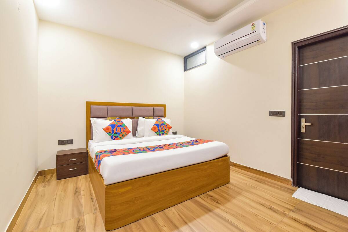 Ein Schlafzimmer mit einem hölzernen Bett, einem Nachttisch, einer Kommode, einer Tür und einer Klimaanlage.