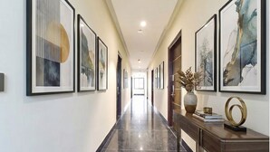 Un pasillo con obras de arte enmarcadas en las paredes, piso de mármol pulido y una consola de madera con adornos.