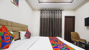 A hotel room with a bed, a chair, a desk, and a TV. - Fabhotel Canal View (Ludhiana)