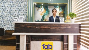 A reception desk with a 'fab hotels' sign, a decorative wall with a floral pattern, and a potted plant. - Fabhotel Canal View (Ludhiana)