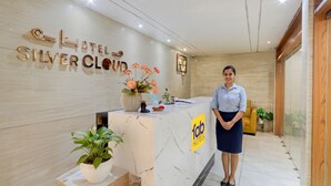 A hotel reception desk with a marble counter, a receptionist, and a sign for 'Silver Cloud Hotel'. - Fabhotel Dsg Residency (Faridabad)