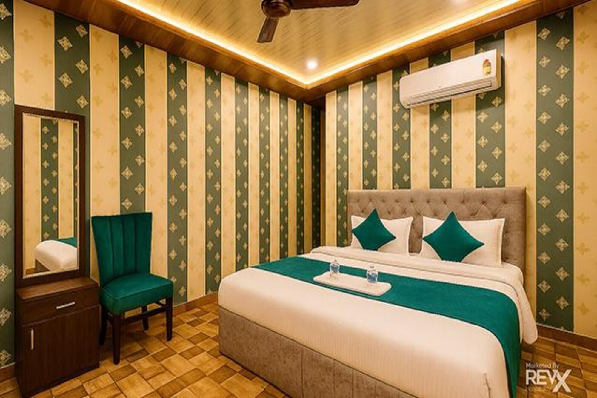 A hotel room with a large bed, a chair, a nightstand, and a ceiling fan.