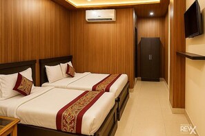 A hotel room with two beds, a wardrobe, a television, and an air conditioning unit. - Fabhotel Balaji (Lucknow)