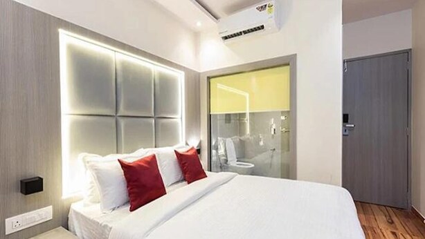 Een moderne hotelkamer met een groot bed, een nachtkastje, een vastgezet hoofdbord en uitzicht op de badkamer.