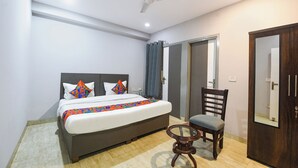 A bedroom with a bed, a chair, a ceiling fan, and a door. - FabHotel Dream Palace (New Delhi)