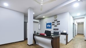 A reception desk with a 'Via' sign, a clock, and various notices on the wall. - FabHotel Dream Palace (New Delhi)