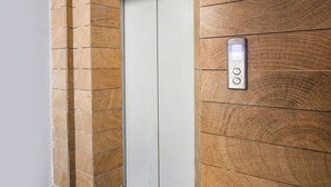 An elevator with a wooden panel design and a control panel with buttons. - FabHotel Dream Palace (New Delhi)