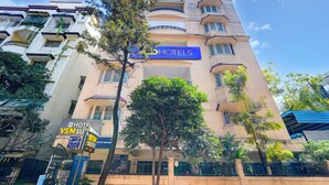 A hotel with a prominent 'HOTELS' sign, surrounded by trees and other buildings. - Fabhotel Vsm Suites (Hyderabad)