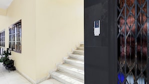 A corridor with a marble staircase, a door with a metal gate, and a wall-mounted intercom. - Fabhotel Vsm Suites (Hyderabad)