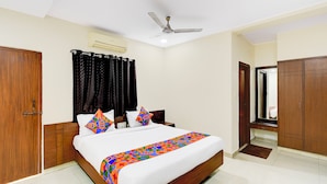 A bedroom with a bed, a ceiling fan, a wardrobe, and a door. - Fabhotel Vsm Suites (Hyderabad)
