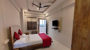 A bedroom with a bed, a ceiling fan, a TV mounted on the wall, and a window with curtains. - Fabhotel Ace Executive (Pune)