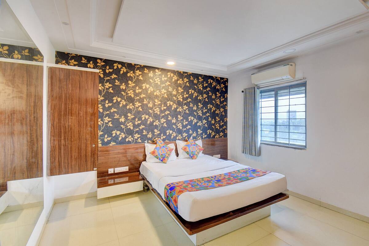 A bedroom with a bed, a wardrobe, a window, and a wall with a leaf pattern.