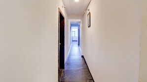Ein schmales, helles Treibhaus mit Marmorboden und einer Deckenleuchte.