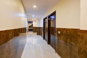 A hallway with marble flooring, dark marble walls, and two doors with numbers 203 and 204. - Fabhotel Golden Key Residency (New Delhi)