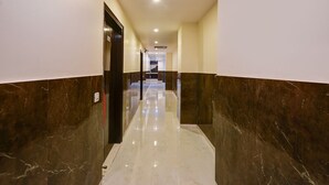 A hallway with marble walls and a shiny floor, leading to a reception area. - Fabhotel Golden Key Residency (New Delhi)