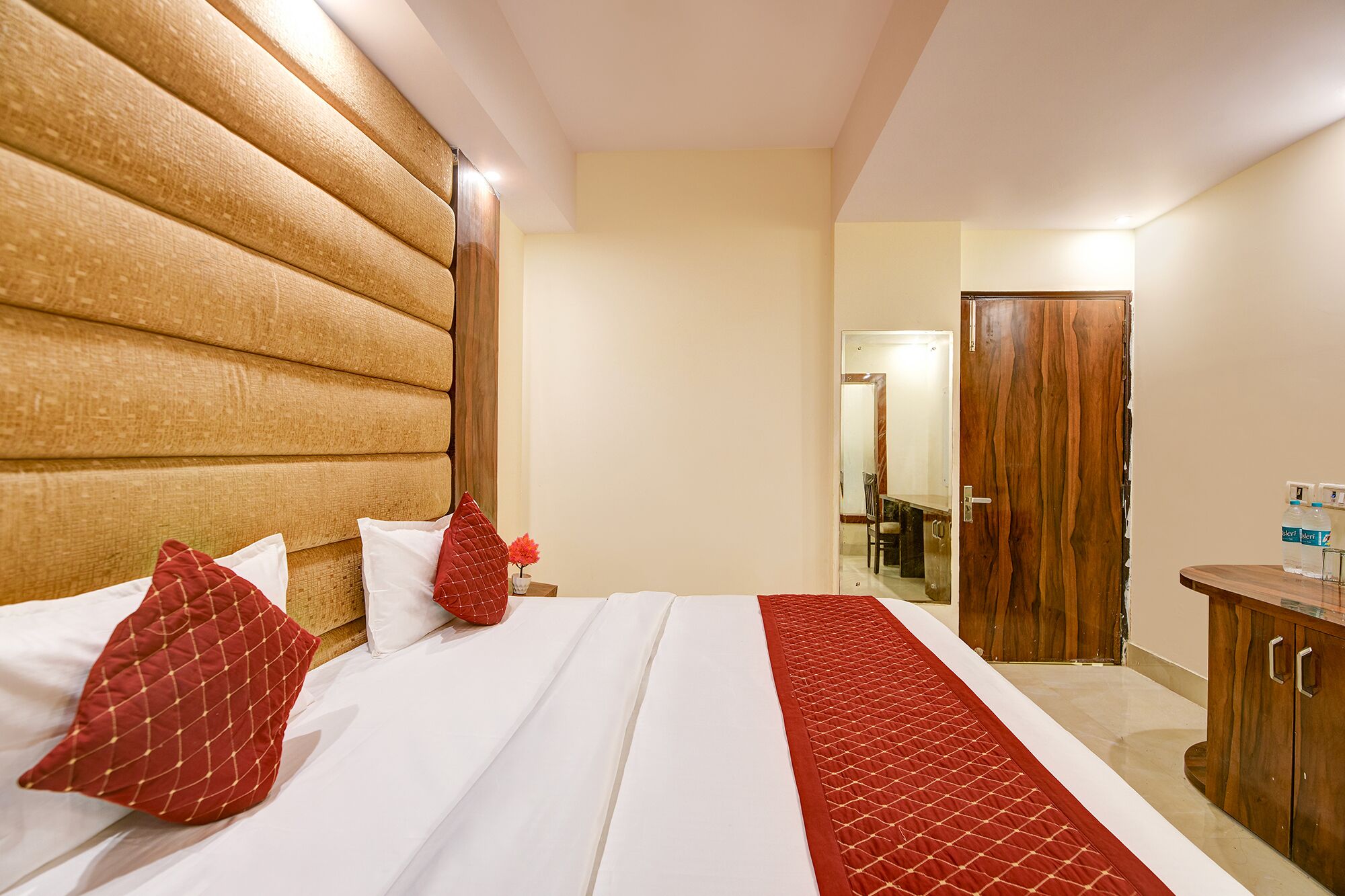 Ein Hotelzimmer mit einem großen Bett, einem Holzkopfstück und einer roten gesteppten Tagesdecke.