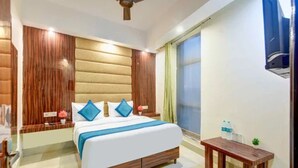 A modern bedroom with a large bed, wooden headboard, bedside tables, and a small wooden bench. - Fabhotel Golden Key Residency (New Delhi)