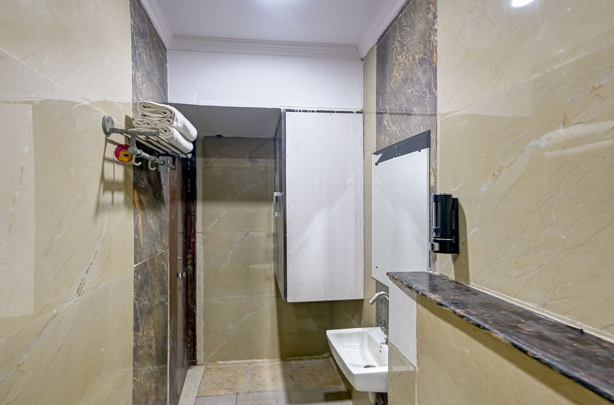 A small bathroom with a sink, a mirror, and a towel rack.