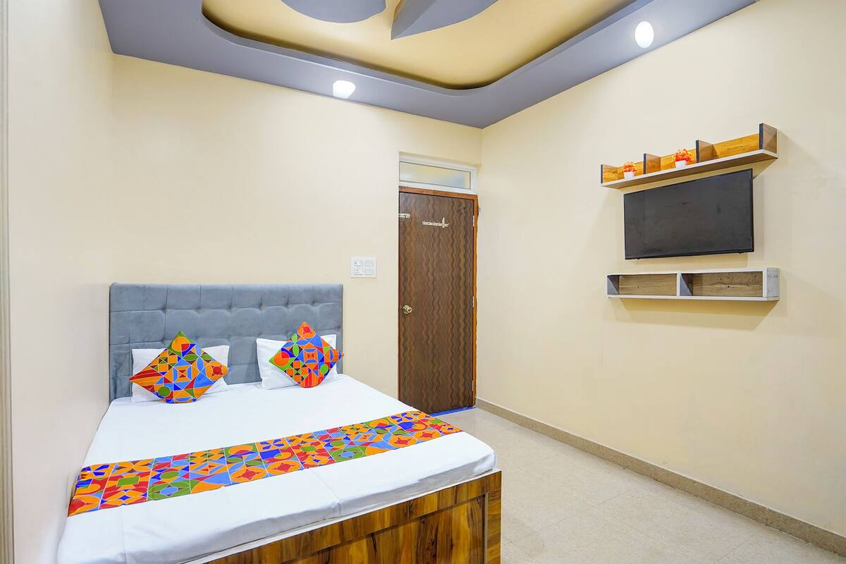 A bedroom with a bed, a TV, and a wooden cabinet.