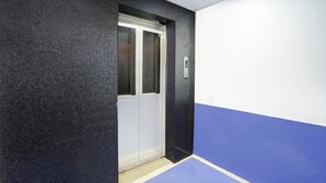 An elevator with a digital display, a door, and a wall with a blue and white color scheme. - Fabhotel Imperial Blue (Nagpur)