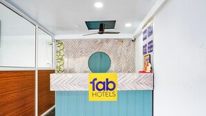 A reception desk with a 'Tab Hotels' sign, a ceiling fan, and a patterned wall. - Fabhotel Imperial Blue (Nagpur)