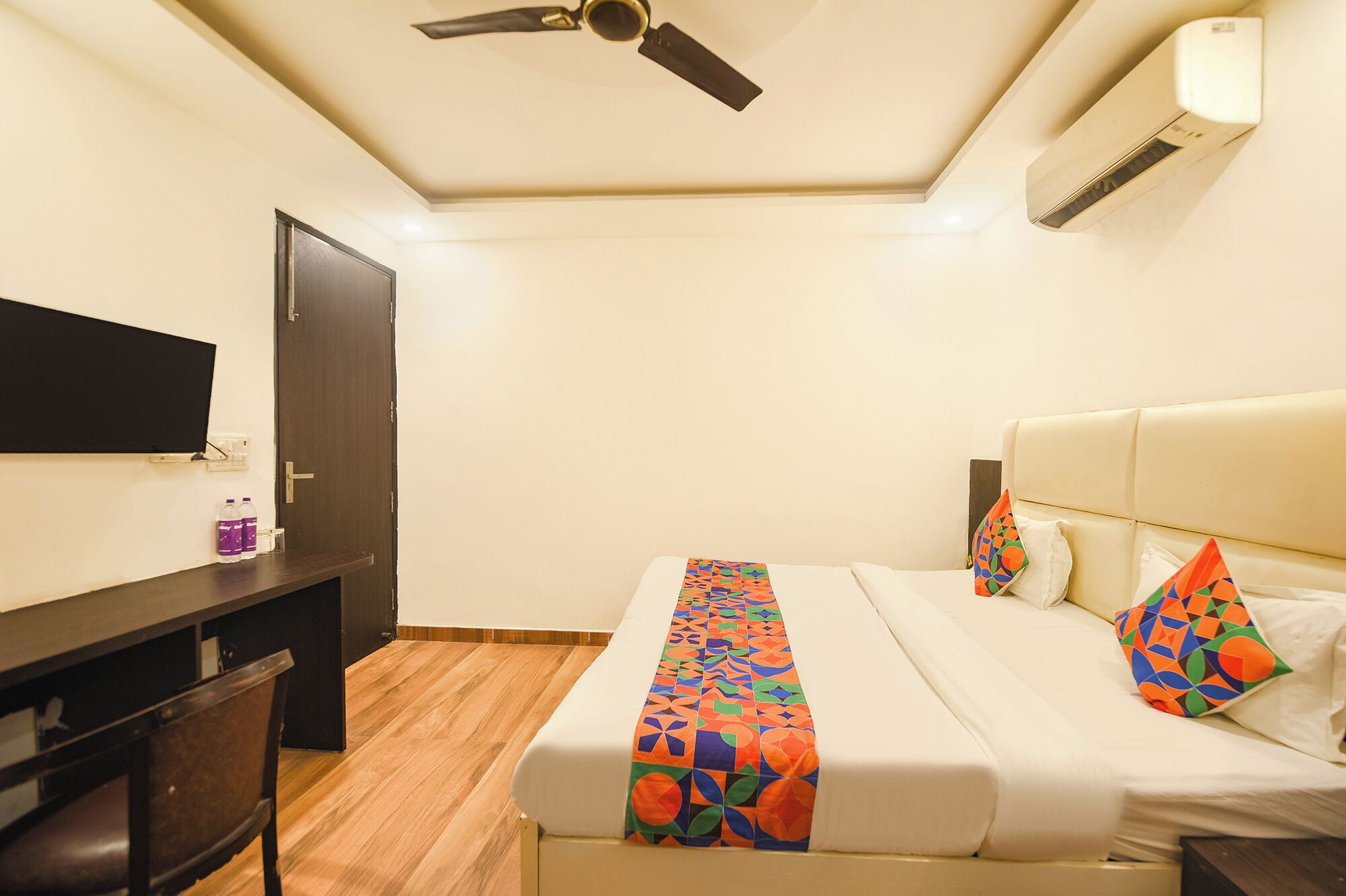 Une chambre d’hôtel équipée d’un lit, d’un bureau, d’une chaise, d’un ventilateur de plafond et d’un appareil de climatisation.