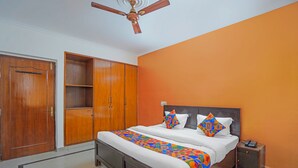 Un dormitorio con cama, armario, ventilador de techo y mesita de noche.