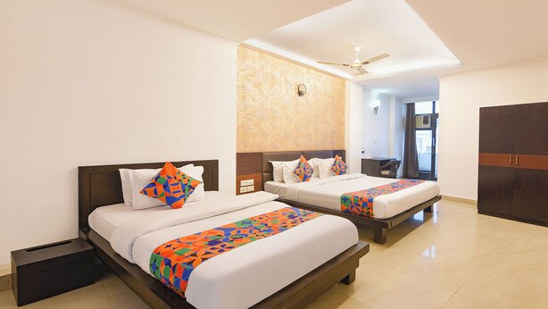 A hotel room with two beds, a ceiling fan, and a large window. - Fabhotel Golden Palm (New Delhi)