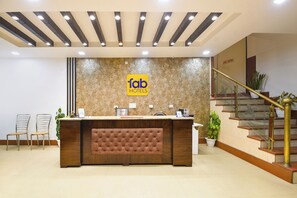 A hotel reception area with a modern design, including a reception desk, a sign for 'Tab Hotels', a staircase with a golden handrail, and a 'Fire Exit' sign. - Fabhotel Golden Palm (New Delhi)